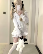 Person wearing a white floral top with thigh-high socks, holding a stuffed animal, presenting a rabbit eared hoodie.
