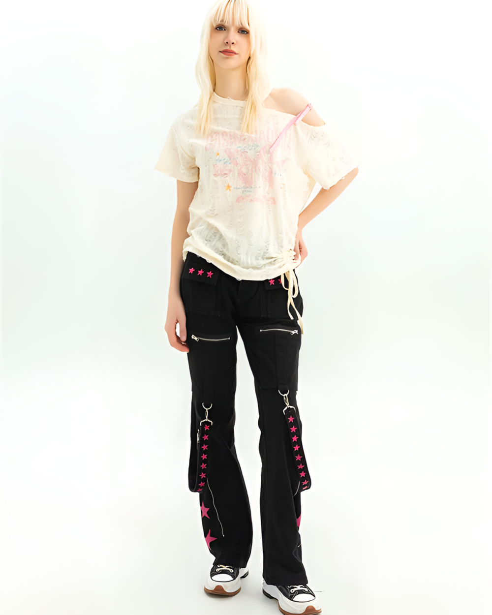 Model wearing black Riot Star-Strap Cargo Pants - Y2K aesthetic with pink star details. These Y2K cargo pants have a low waist and bootcut leg.