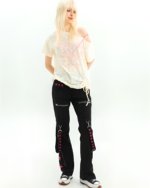 Woman modeling black Riot Star-Strap Cargo Pants, a style of Y2K cargo pants with pink star details and a low rise fit.