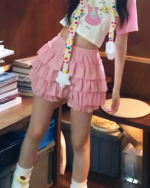 Pink ruffled mini skirt paired with a colorful cropped top and cardigan.