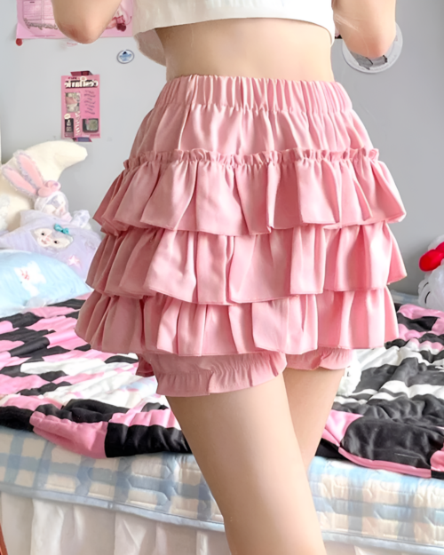 Pink ruffled mini skirt worn by a person, featuring multiple layers and a tiered design.