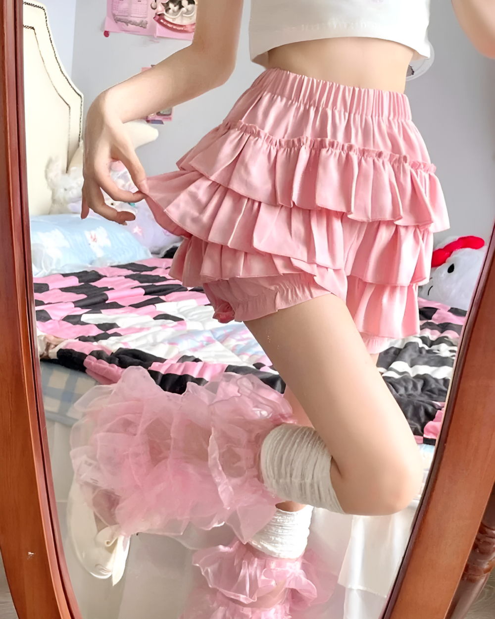 Pink ruffled mini skirt worn by a person, featuring layered ruffles and a high waist.