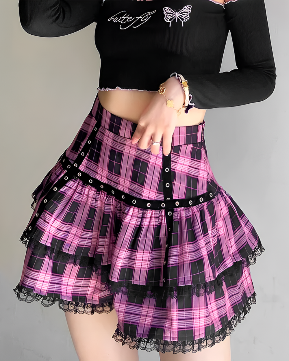 Model wearing a pink plaid mini skirt with a ruffled hem and lace detailing, part of a Mall Goth aesthetic.