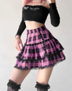Woman wearing a ruffled pink plaid mini skirt with a black lace trim and studded belt, paired with a black crop top.