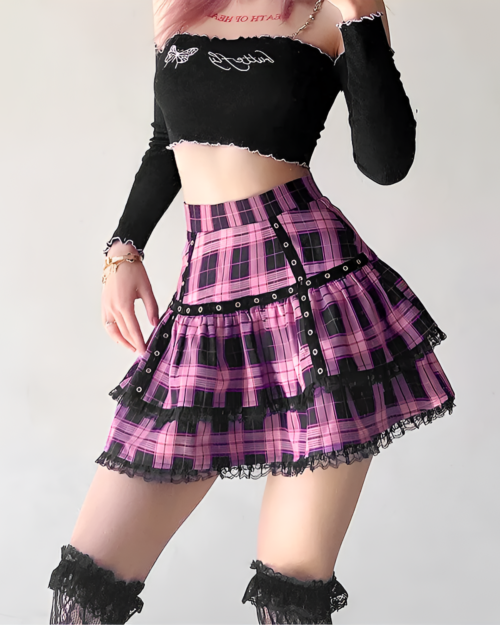 Woman wearing a ruffled pink plaid mini skirt with a black lace trim and studded belt, paired with a black crop top.