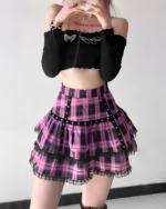 Model wearing a pink plaid mini skirt with a black top and choker. Ruffled details and silver chain belt accentuate the skirt.