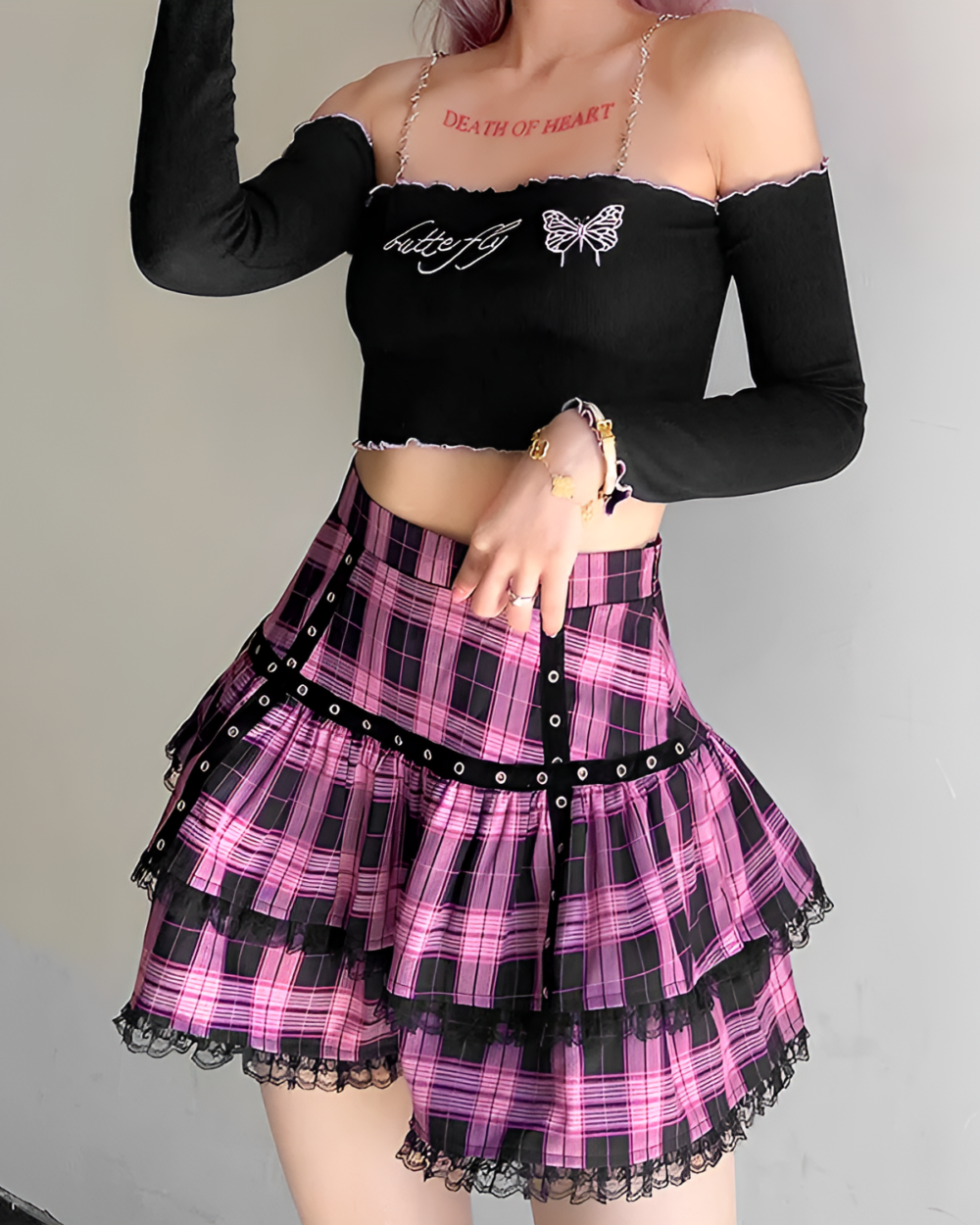 Model wearing a black top and a ruffled pink plaid mini skirt with lace trim. Ideal for a mall goth aesthetic.