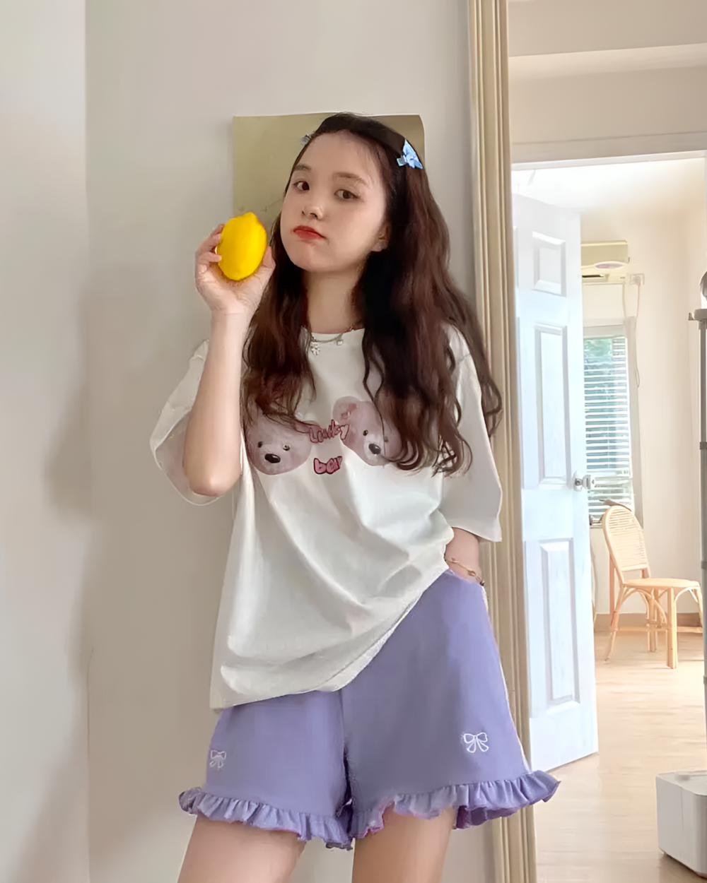 Woman wearing Ruffled Yume Kawaii shorts, a graphic tee, and holding a lemon.