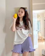 Woman wearing Ruffled Yume Kawaii shorts, a graphic tee, and holding a lemon.