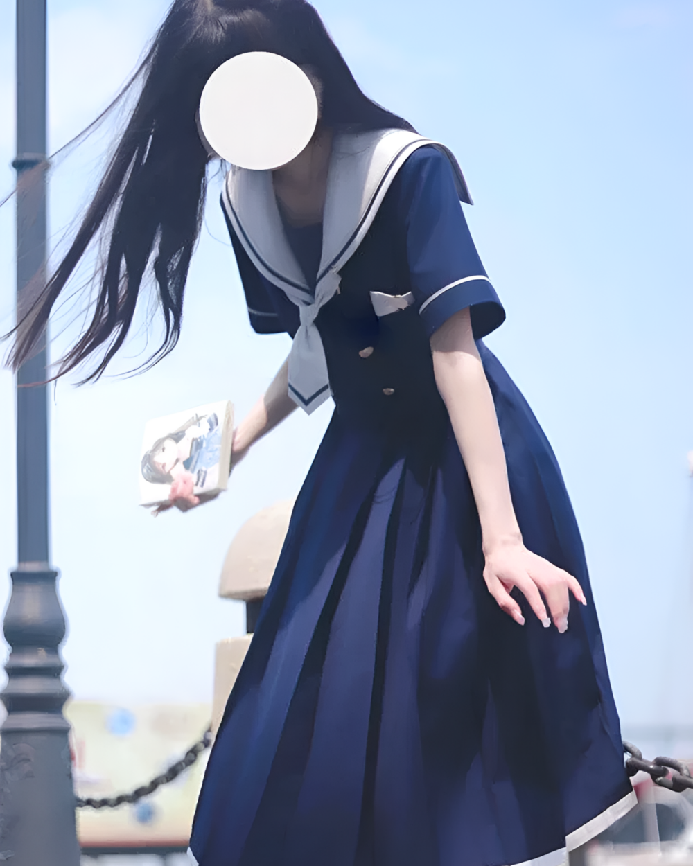 A young woman wearing a blue sailor uniform dress on an outdoor day.