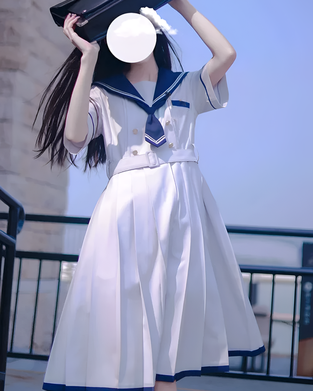 Woman wearing a sailor uniform dress, Nanchatte Seifuku, white pleated dress with blue accents.
