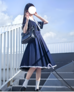 A blue sailor uniform dress (seifuku) with a black bag and white socks, outdoors.