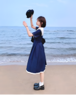 A young woman wearing a navy sailor uniform dress by the beach.