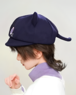 Side view of a person wearing a navy blue Scarameow Beret with cat ears and a tail detail.