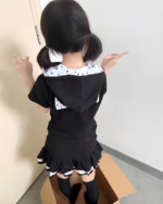 Back view of a person wearing a black Sleepy Neko short sleeved hooded t-shirt with white polka dots and a ruffled hem.