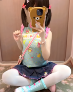 Girl wearing a sleeveless blue Mezzo Piano top with a print and denim skirt, showcasing the Mezzo Piano top's design.