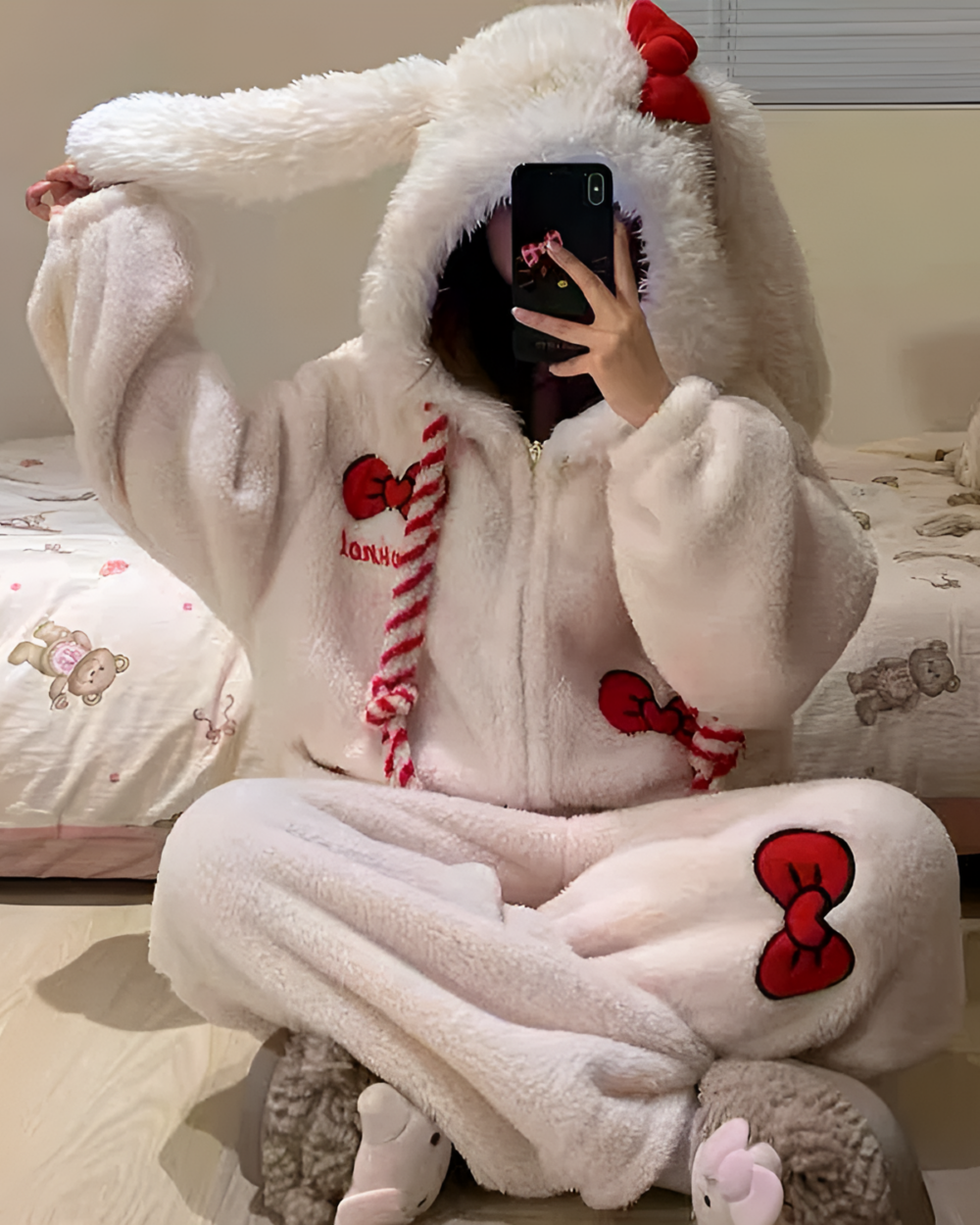 Person wearing a white Slumber Bow-Bunny Ribbon Kigurumi Pajamas, a fluffy bunny kigurumi with a red ribbon and heart details.