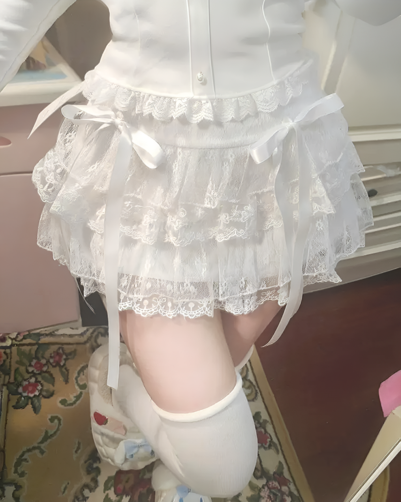 White soft girl aesthetic skirt with lace details and bowties. Layered tulle and delicate straps.