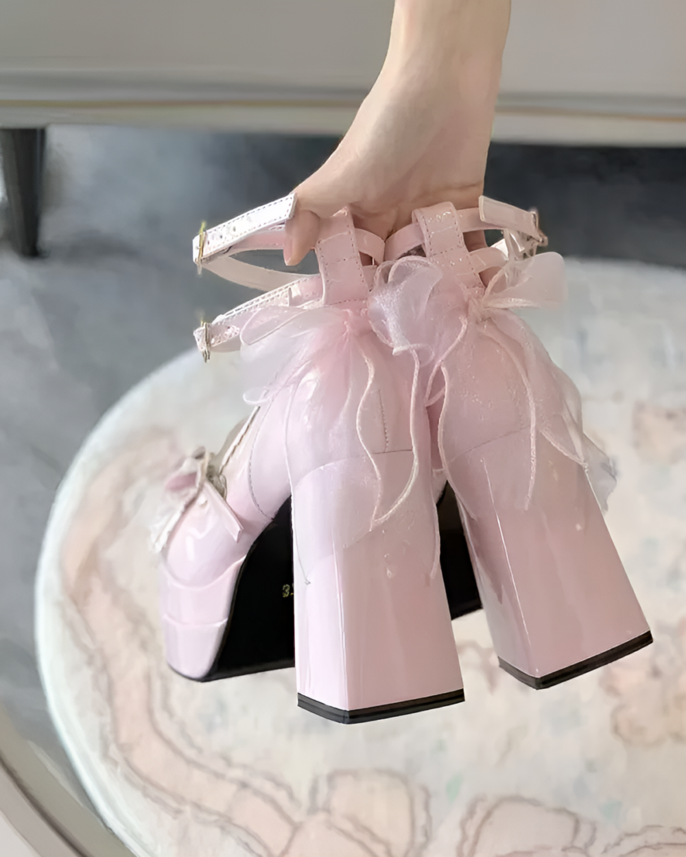 Close-up of pink Starlit Lace-Bow Mary Janes with a platform heel and lace detailing, held in hand.
