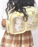 Person wearing a beige Strapped JK Ita Bag with a clear window displaying a plush toy and character decorations.