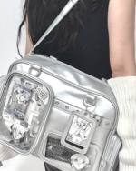 Silver Strapped JK Ita Bag with clear panel displaying anime keychains and stickers, worn as a shoulder bag.