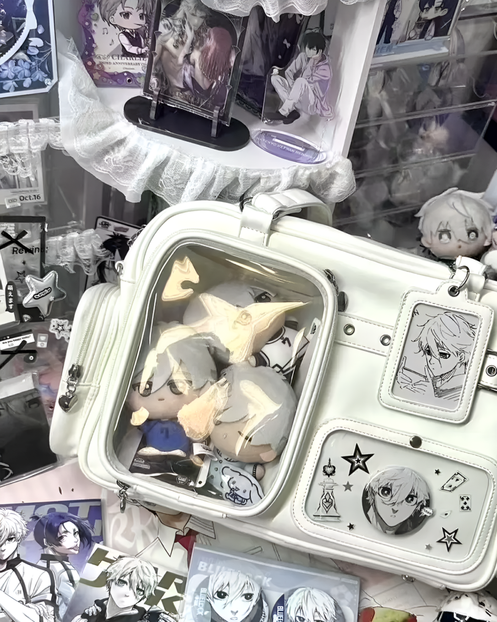 Clear Strapped JK Ita Bag displayed with anime character keychains and merchandise. The bag features a transparent window for displaying items.