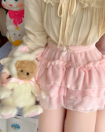 Close-up of a pink Sweet Lolita Plush Skirt with lace trim and ruffles, alongside plush toys.