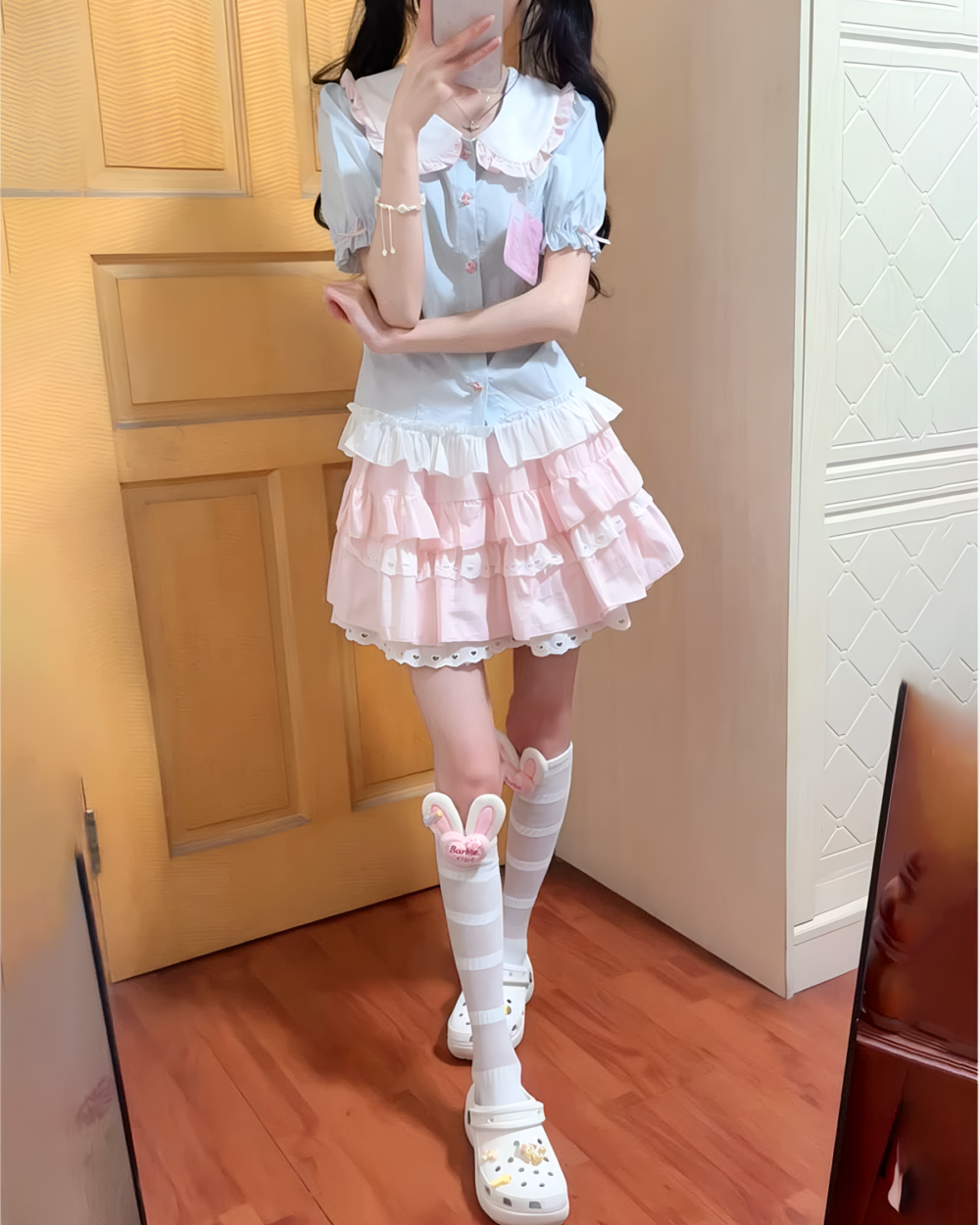 A young woman wearing a Sweet Lolita School Suit, pink skirt, and white socks with bunny clips.