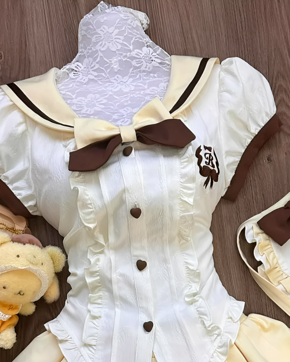 Close-up of a Sweet Lolita set - Pudding Edition, featuring a cream-colored blouse with lace details and a brown bow.