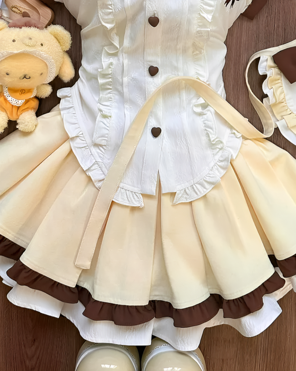 Close-up of a Sweet Lolita set - Pudding Edition, featuring a cream blouse and layered brown skirt with ruffles.