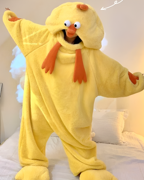 Person wearing a yellow Chicken Kigurumi pajama suit with a hood and beak. Comfortable and fluffy onesie for cosplay or lounging.