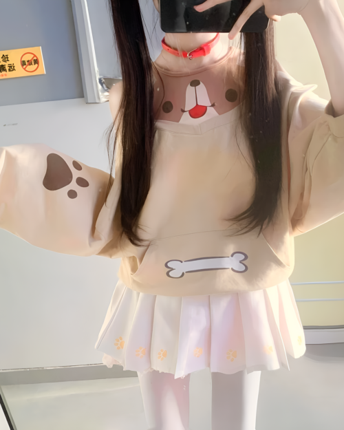 Person wearing a beige Doggy Sweatshirt with paw prints and a pleated pink skirt. The sweatshirt has a cute dog face design.
