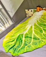 The Lettuce Blanket draped over a bed, featuring a large lettuce design.