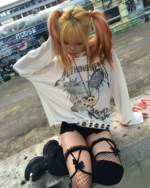 A person wearing a white Transluscent Nothingness T-Shirt with a graphic design, styled with black boots and skirt.