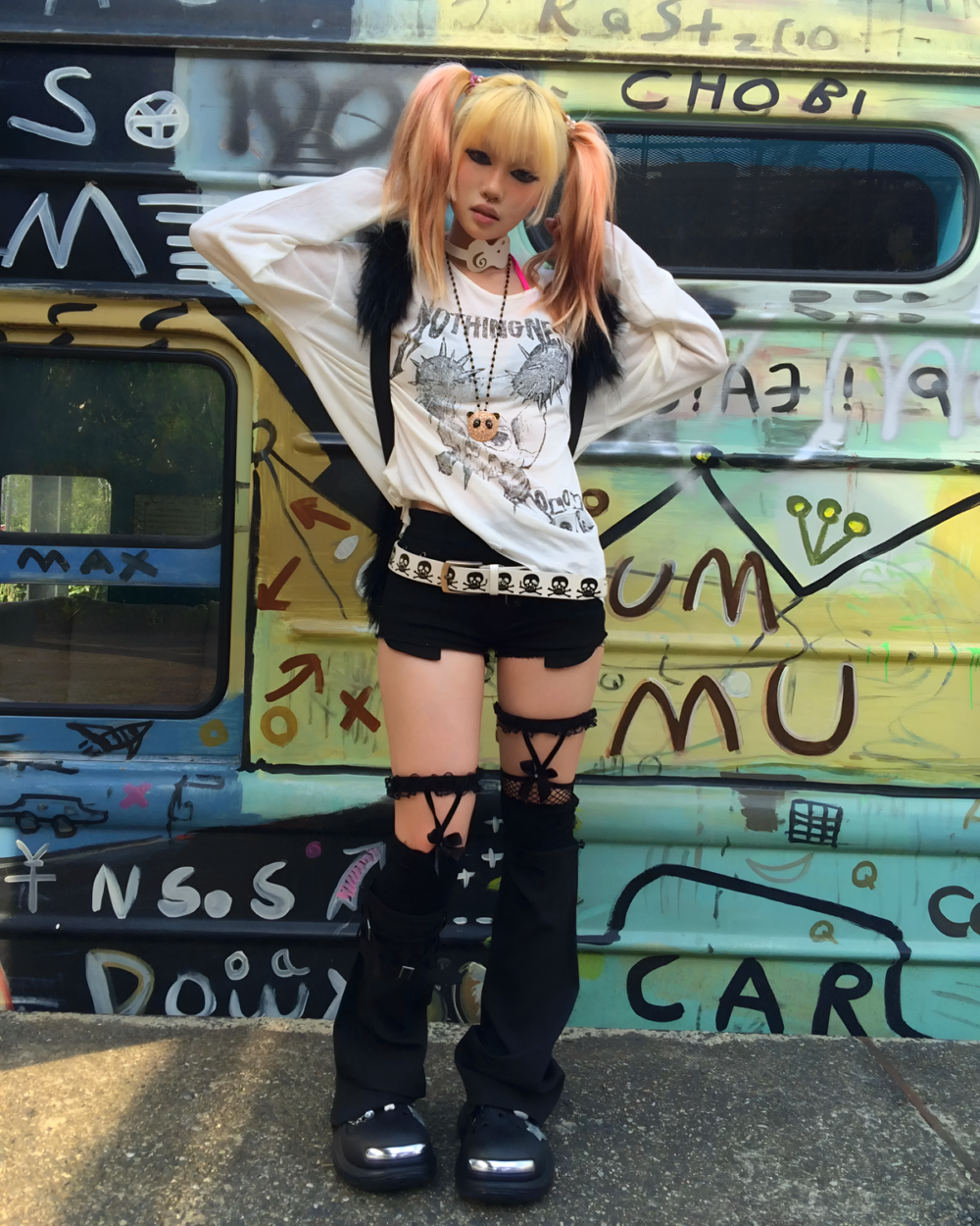 Person wearing a white Transluscent Nothingness T-Shirt with a black vest and black shorts against a graffiti wall.