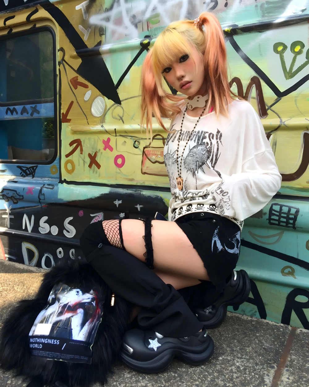 Woman wearing a white Transluscent Nothingness T-Shirt and black boots, posing in front of graffiti. The T-shirt features a skull design.