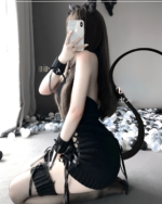 Woman wearing a black turtleneck virgin killer lingerie set with a tail and gloves, posing with a phone.