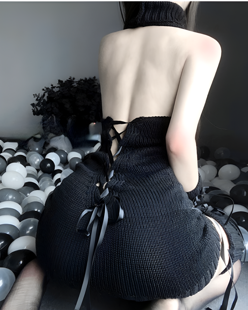 Back view of a woman wearing a black turtleneck virgin killer lingerie with tie details.