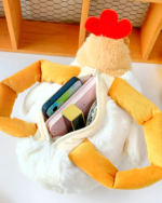 Close-up of the yellow ugly chicken plush handbag open, showing space for a phone, wallet, and cosmetics.