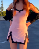 Woman wearing a pink Velvet Vamp Mini Dress with black lace trim. The dress has a v-neck and a short hemline.