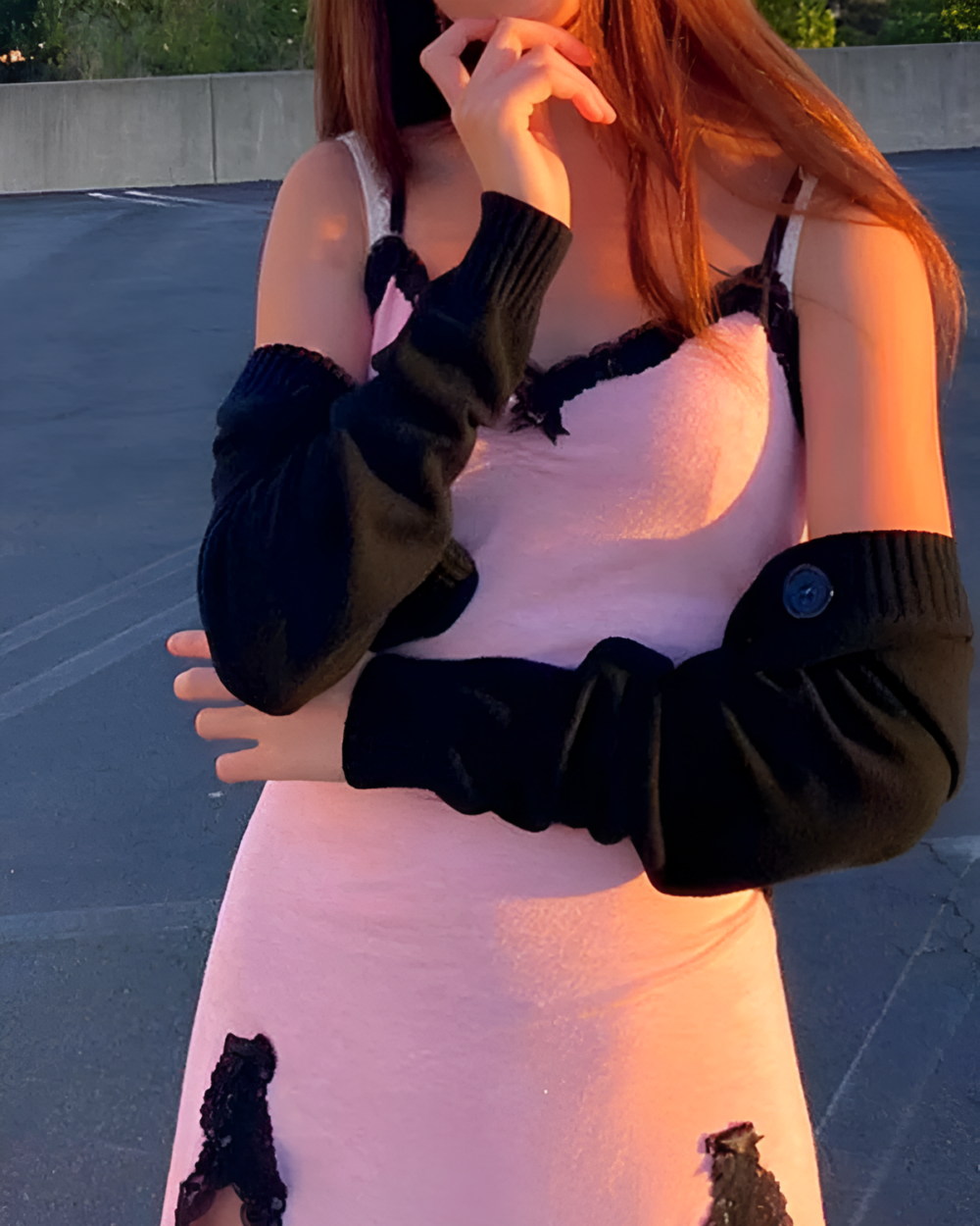 Woman wearing a pink Velvet Vamp Mini Dress with black sleeves and lace detailing. A stylish and feminine dress.