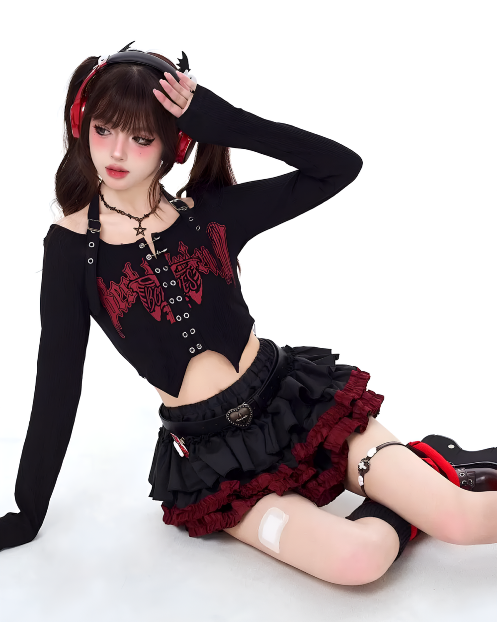Model wearing the Venom Heart Ruffle Skirt set, a black long sleeve top and ruffle mini skirt with red heart details.