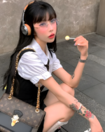 Model wearing a white blouse and black suspender skirt set. The outfit includes a suspender skirt set and a gold chain.