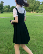Woman wearing a black suspender skirt set and white blouse outdoors. It's a vibrant look for a casual day.
