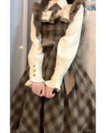 Close-up of a vintage midi cottagecore dress with ruffled sleeves and a plaid skirt.