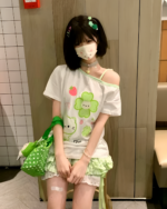 Model wearing a Yotsuba Neko T-Shirts - Jojifuku Aesthetic, featuring a cute green neko design.