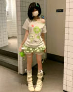 Model wearing Yotsuba Neko T-Shirts with cat and flower designs, pastel aesthetic.