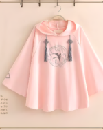 Pink Zephyr Bamboo hooded poncho with embroidery detail, hanging on a rack. A lightweight hooded poncho.