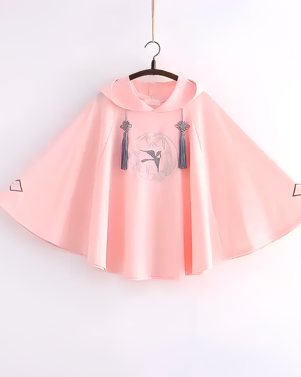 Pink Zephyr Bamboo hooded poncho hanging on a hanger, featuring tassel details.